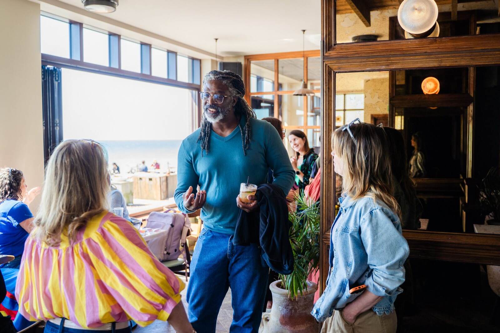 A guest in a blue jumper talking with people at a house of hopium gathering